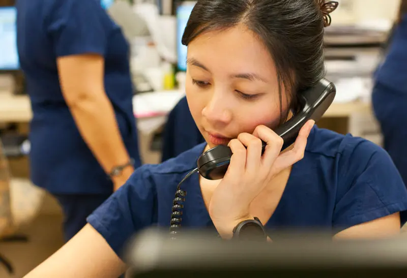 A medical worker talks to a patient with an interpreter's help on the phone.
